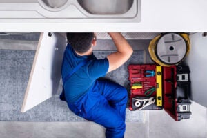 A plumber of Kevin Ginnings Plumbing is fixing a wash basin in Kansas City.