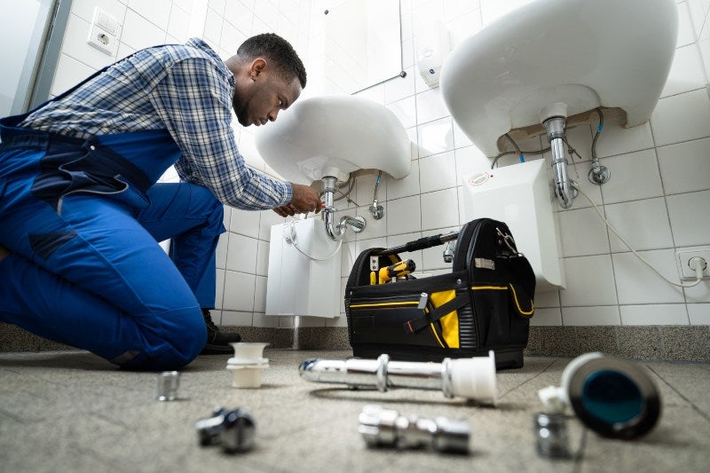 An expert plumber repairing a sink in in South Kansas, MO