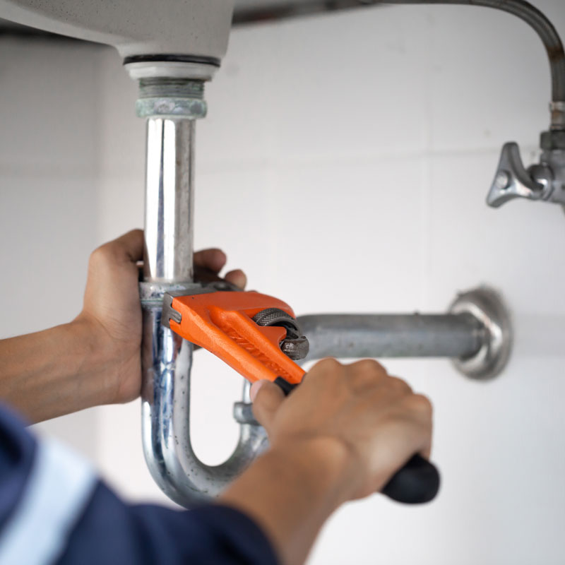 plumber repairing a pipe under a sink