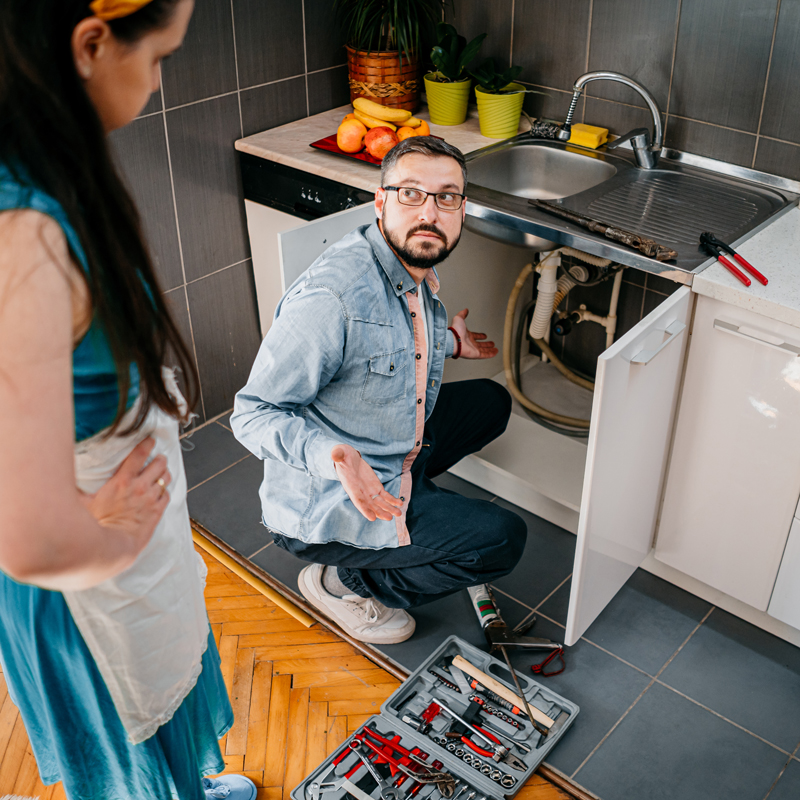 man looking at lady because he cant repair the sink