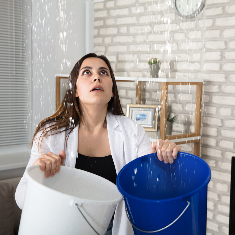lady with buckets catching water falling from a leak